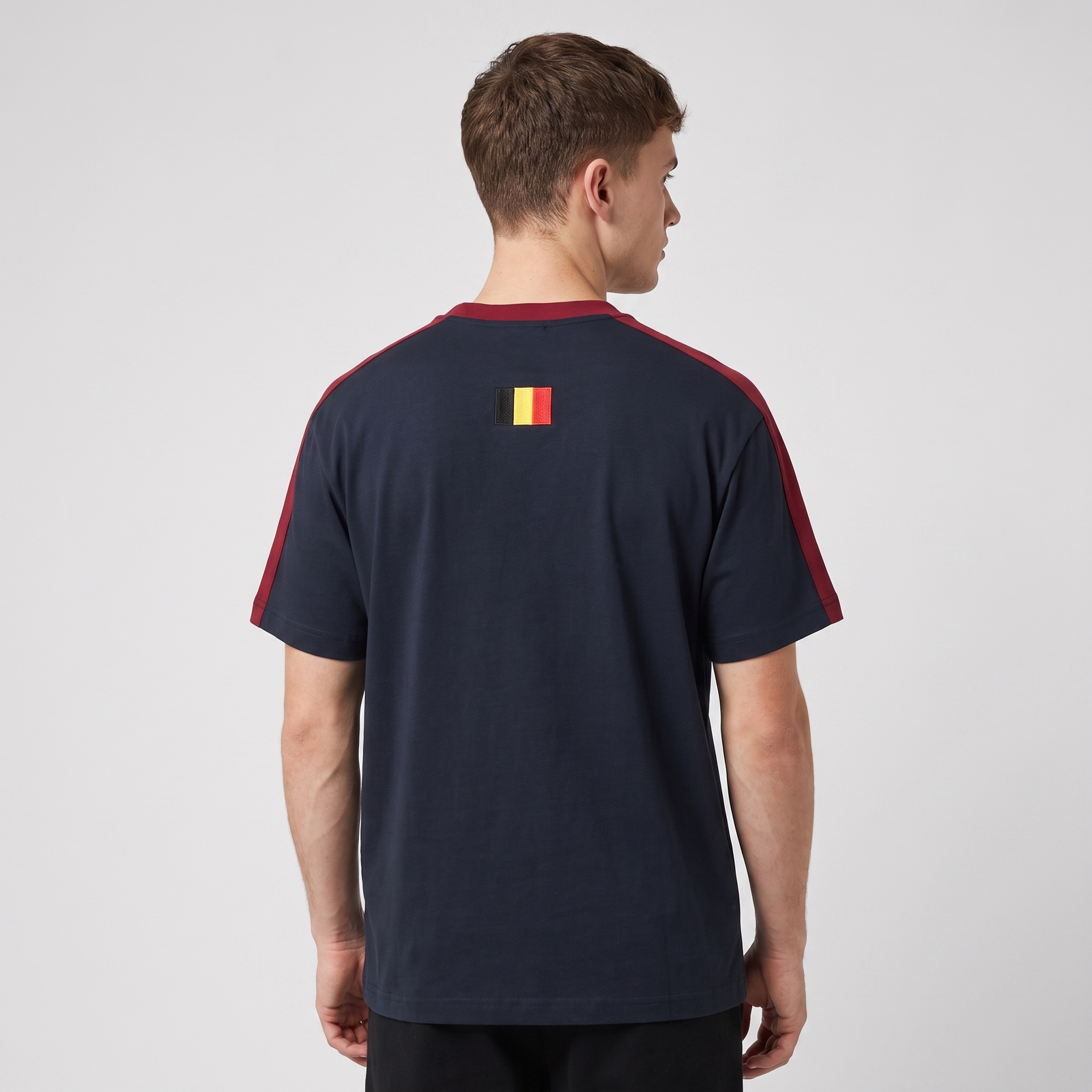 Homme portant le t-shirt Le Pays de la Bière bleu marine en studio photo carré - vue de dos avec drapeau belge brodé