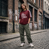 Femme streetwear portant le t-shirt Le Pays de la Bière rouge bordeaux dans une rue belge - format carré