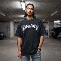T-shirt oversized noir delave au lettrage gothique blanc LEGACY, porte dans un parking souterrain en beton brut