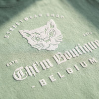 Gros plan sur l'impression blanche du chat gothique et du lettrage Belgium sur le coton vert amande