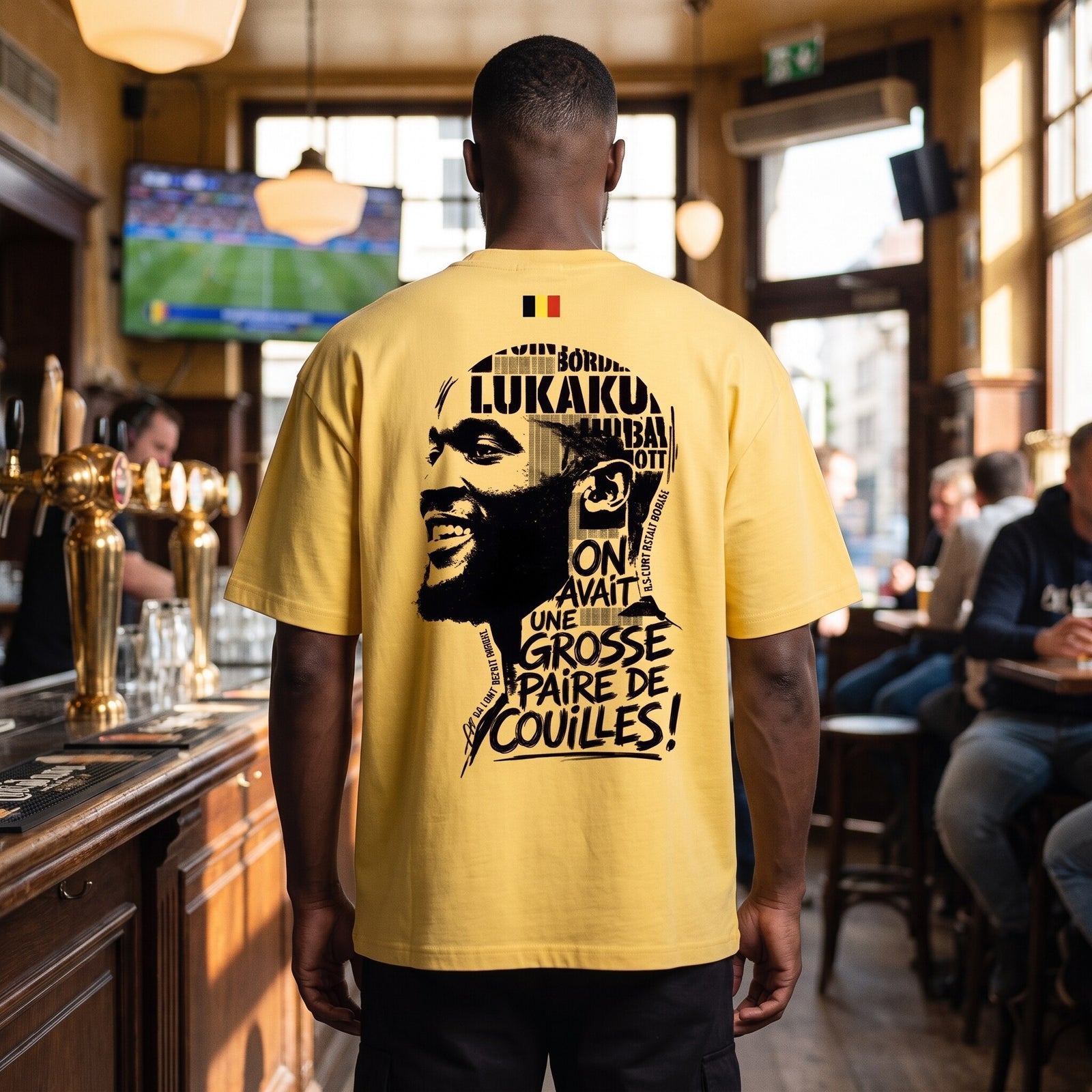 Vu de dos dans un estaminet belge, le t-shirt jaune affiche le drapeau national et l'imprime Lukaku pleine largeur