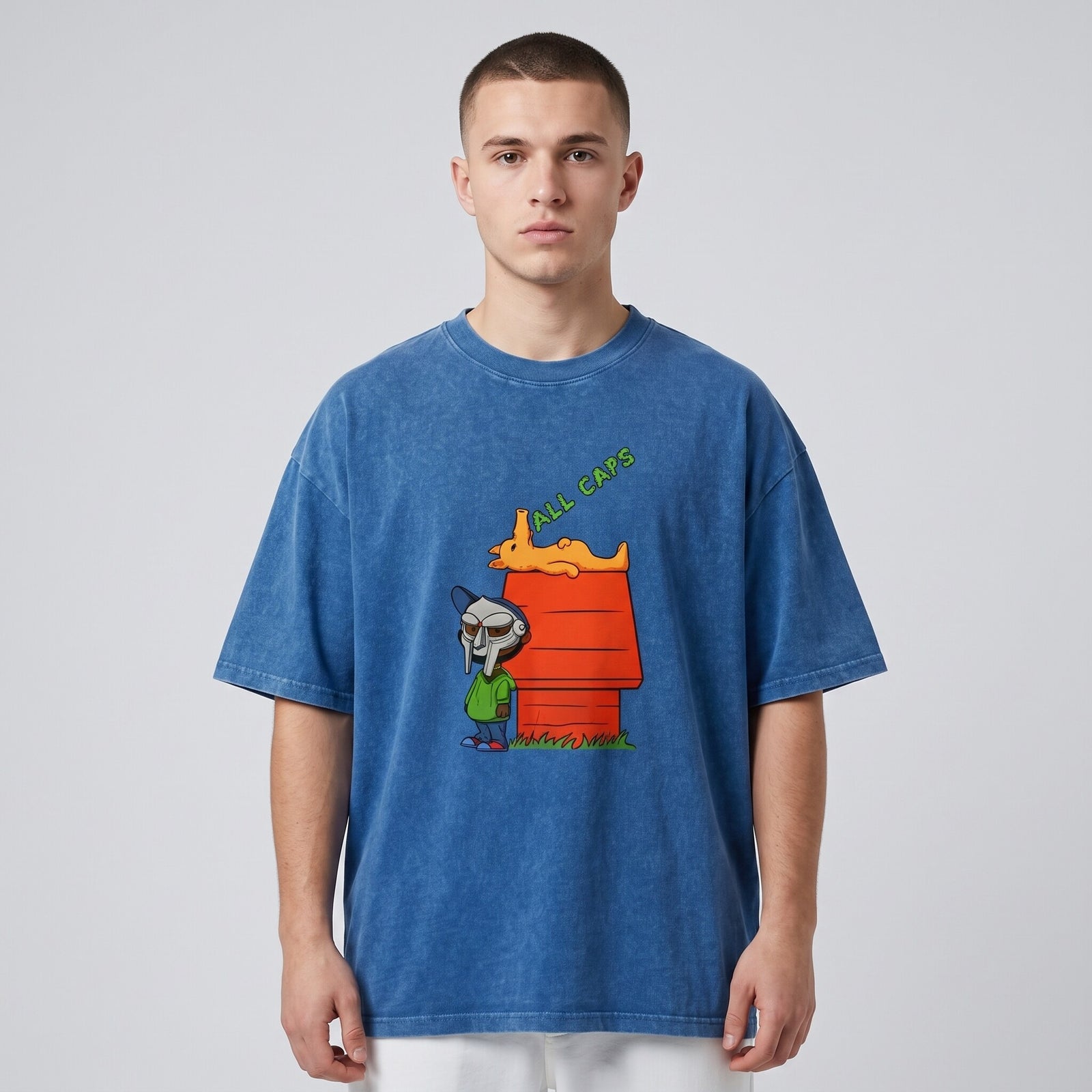T-shirt oversized bleu snow wash à l'imprimé cartoon All Caps, porté en studio devant un fond gris clair