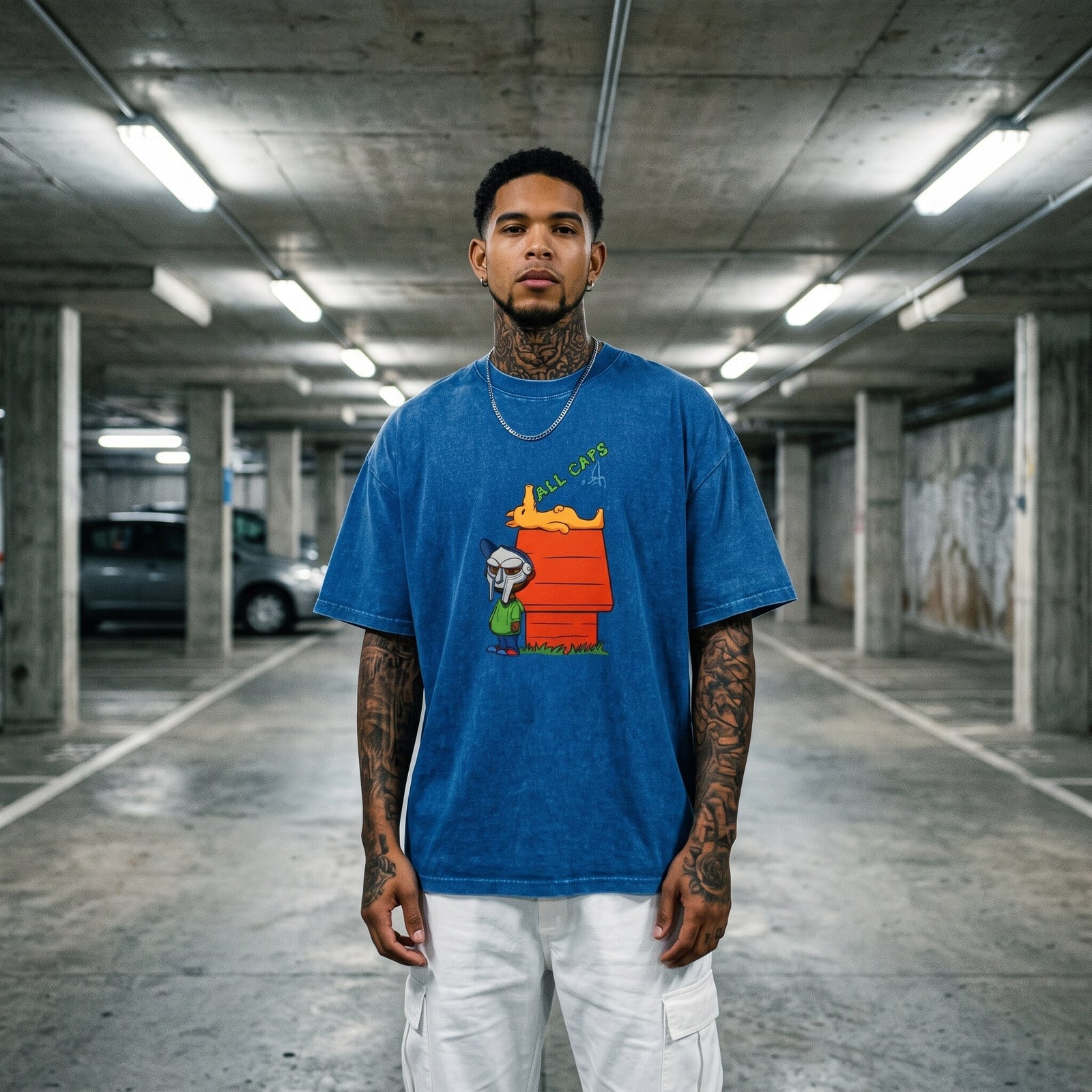 T-shirt oversized bleu délavé All Caps, porté au milieu d'un parking souterrain en béton sous les néons