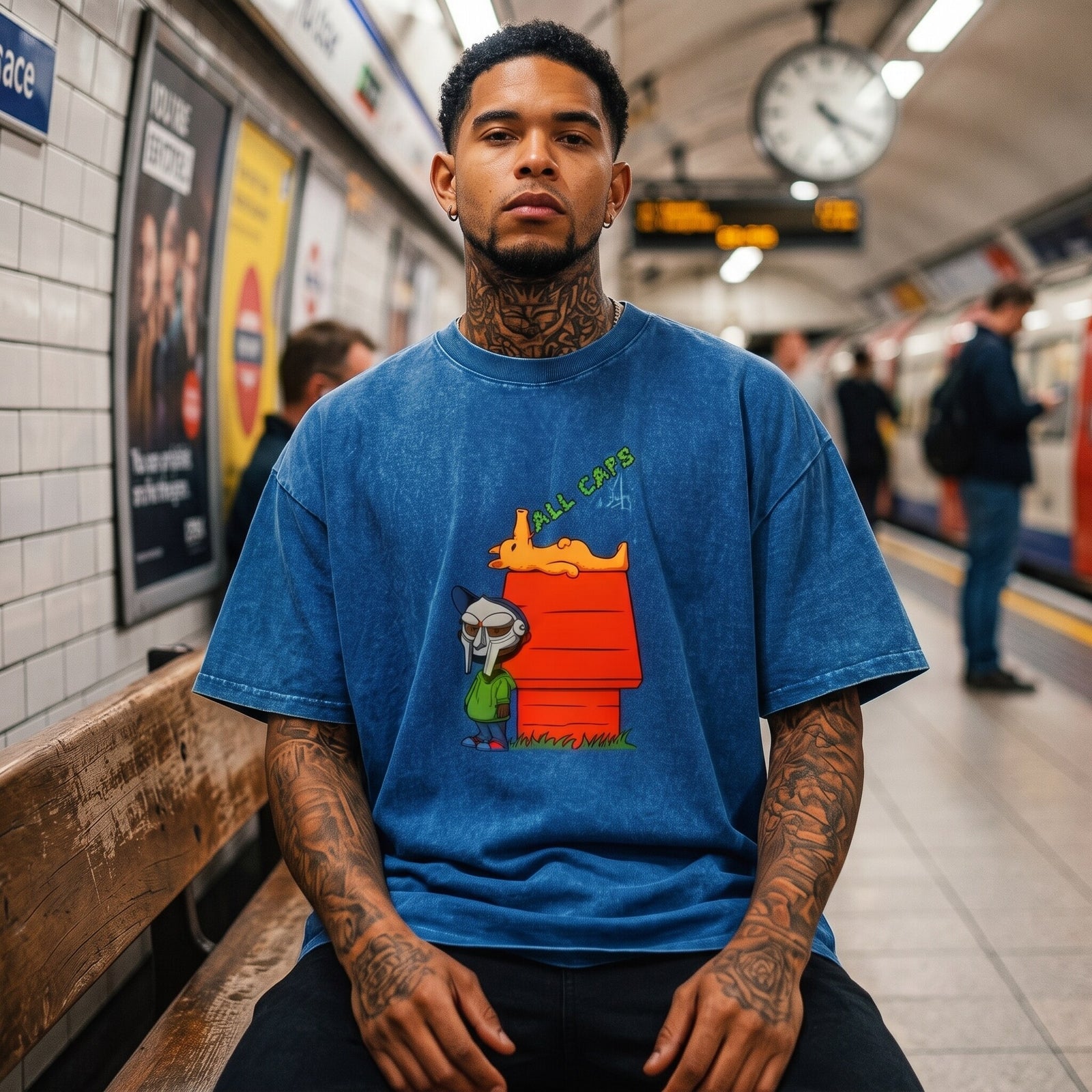 T-shirt oversized bleu délavé hommage à MF DOOM, porté assis sur un banc dans une station de métro carrelée