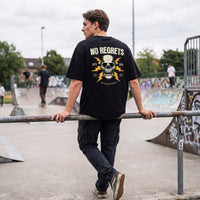 Crâne No Regrets et éclairs jaunes imprimés au dos d'un t-shirt noir, porté au milieu des rampes d'un skatepark