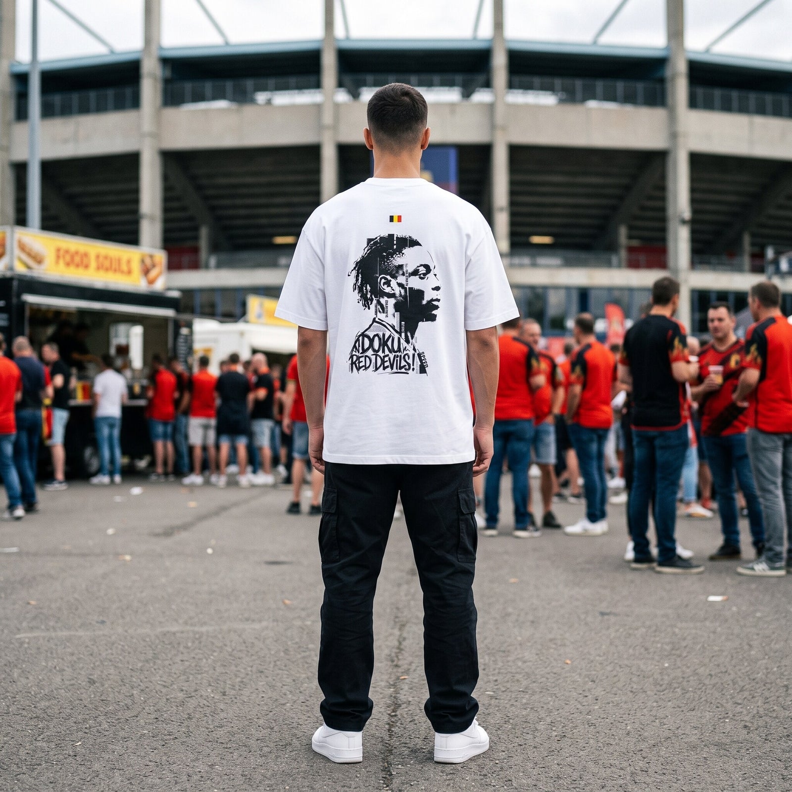 T-shirt oversized blanc vu de dos, portrait de Doku, porte devant un stade au milieu des supporters en rouge