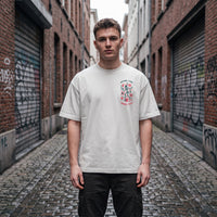 T-shirt oversized blanc casse Dying For Some Fun, porte dans une ruelle pavee bordee de rideaux metalliques tagues