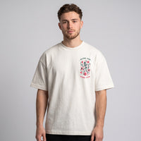 T-shirt oversized blanc casse au petit logo squelette festif sur la poitrine, porte en studio sur fond gris clair