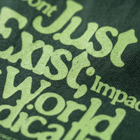 Gros plan sur le lettrage vert clair Don't Just Exist imprime sur le coton vert fonce d'un t-shirt en coton lourd