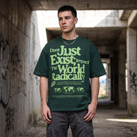 T-shirt oversized vert fonce au lettrage seventies vert clair, porte sous une dalle de beton couverte de graffitis