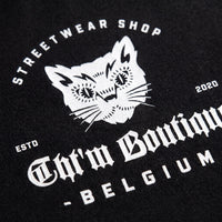 Gros plan sur la tete de chat blanche et le lettrage Streetwear Shop Belgium imprimes sur du coton noir