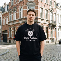 T-shirt oversized noir au logo chat blanc CHT'M Boutique Belgium, porte a un coin de rue pavee bruxelloise