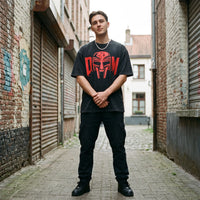 T-shirt oversized noir délavé au masque MF DOOM rouge XXL, porté dans une ruelle pavée aux volets métalliques