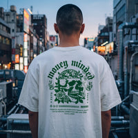 Dos d'un t-shirt oversized blanc au grand crane vert Money Minded, porte dans une rue japonaise au crepuscule