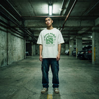 T-shirt oversized blanc Money Minded porte avec un jean baggy dans un parking souterrain eclaire au neon
