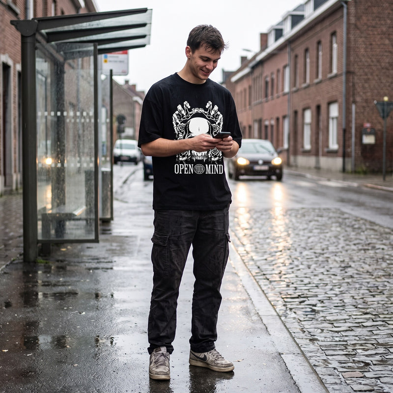 T-shirt oversized noir Open Your Mind à crâne et roses blanches, porté sous un abribus un jour de pluie