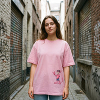 T-shirt oversized rose pale, panthere rose a lunettes en bas du buste, porte dans une ruelle pavee de Bruxelles