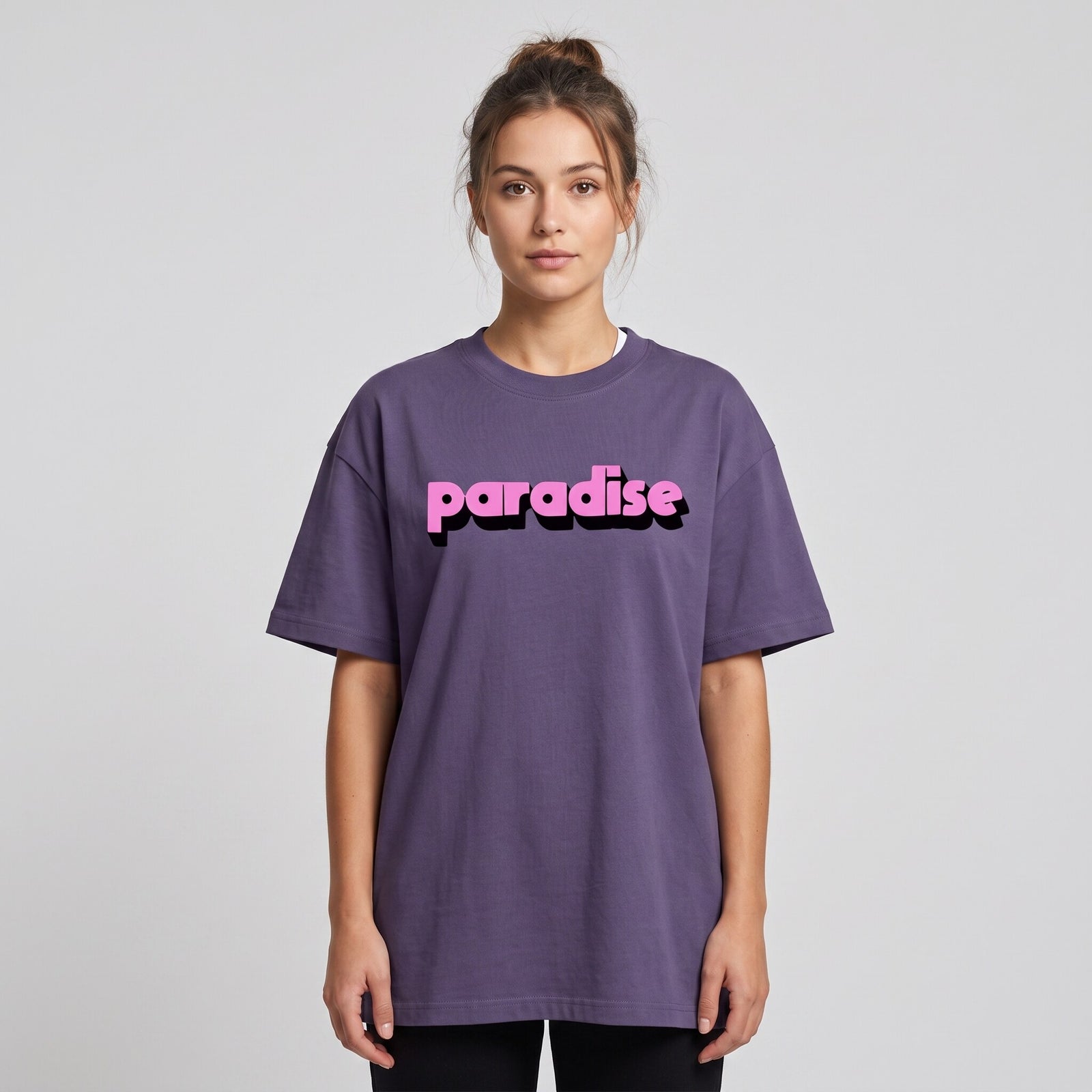 T-shirt oversized violet brume au lettrage rose bonbon paradise, porte par une femme sur fond de studio gris
