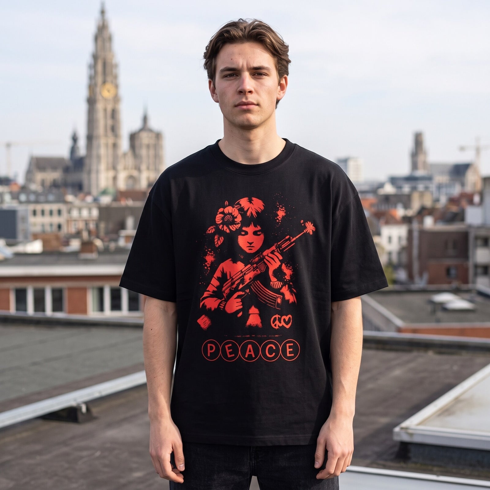 T-shirt noir Peace au lettrage rouge cerclé, porté sur une toiture avec la flèche de la cathédrale derrière