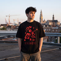 Coupe oversized noire et illustration Peace rouge, portée sur un toit au coucher du soleil au-dessus des toits
