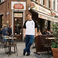 T-shirt raglan blanc et noir au logo DAD chope de biere, porte en terrasse d'un cafe bruxellois pave