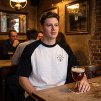 T-shirt raglan blanc et noir DAD Beer, porte attable dans un cafe brun belge devant un verre de biere