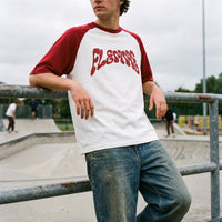 T-shirt raglan blanc, gros lettrage psychédélique bordeaux FLEMME, cadrage serré avec jean délavé au skatepark
