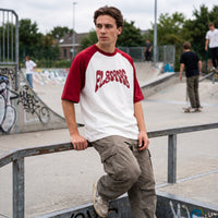 T-shirt raglan FLEMME blanc et bordeaux porté avec un cargo beige au bord d'un bowl couvert de graffitis