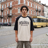 T-shirt raglan ecru a manches noires Made in Belgium Non peut-etre, porte dans une rue bruxelloise avec un tram