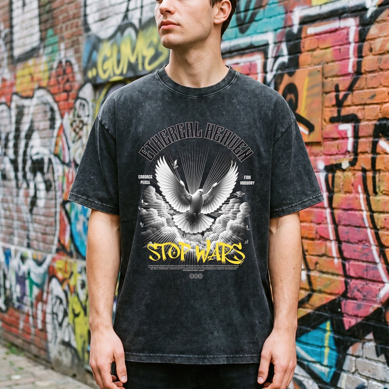 T-shirt oversized noir délavé à colombe de la paix, porté dans une ruelle bordée de briques et de tags colorés