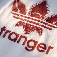 Macro du logo stranger rouge craquele imprime sur le coton blanc, texture du tissu bien visible