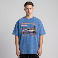 T-shirt oversized bleu délavé à l'imprimé voiture de drift Tokyo Turbo, porté en studio sur fond gris uni
