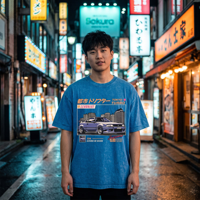 T-shirt oversized bleu délavé Tokyo Turbo, porté dans une ruelle de Tokyo illuminée par les enseignes au néon