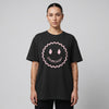 T-shirt Dour Festival DOUREUUUH oversize noir porté par une femme, smiley acid holographique, studio