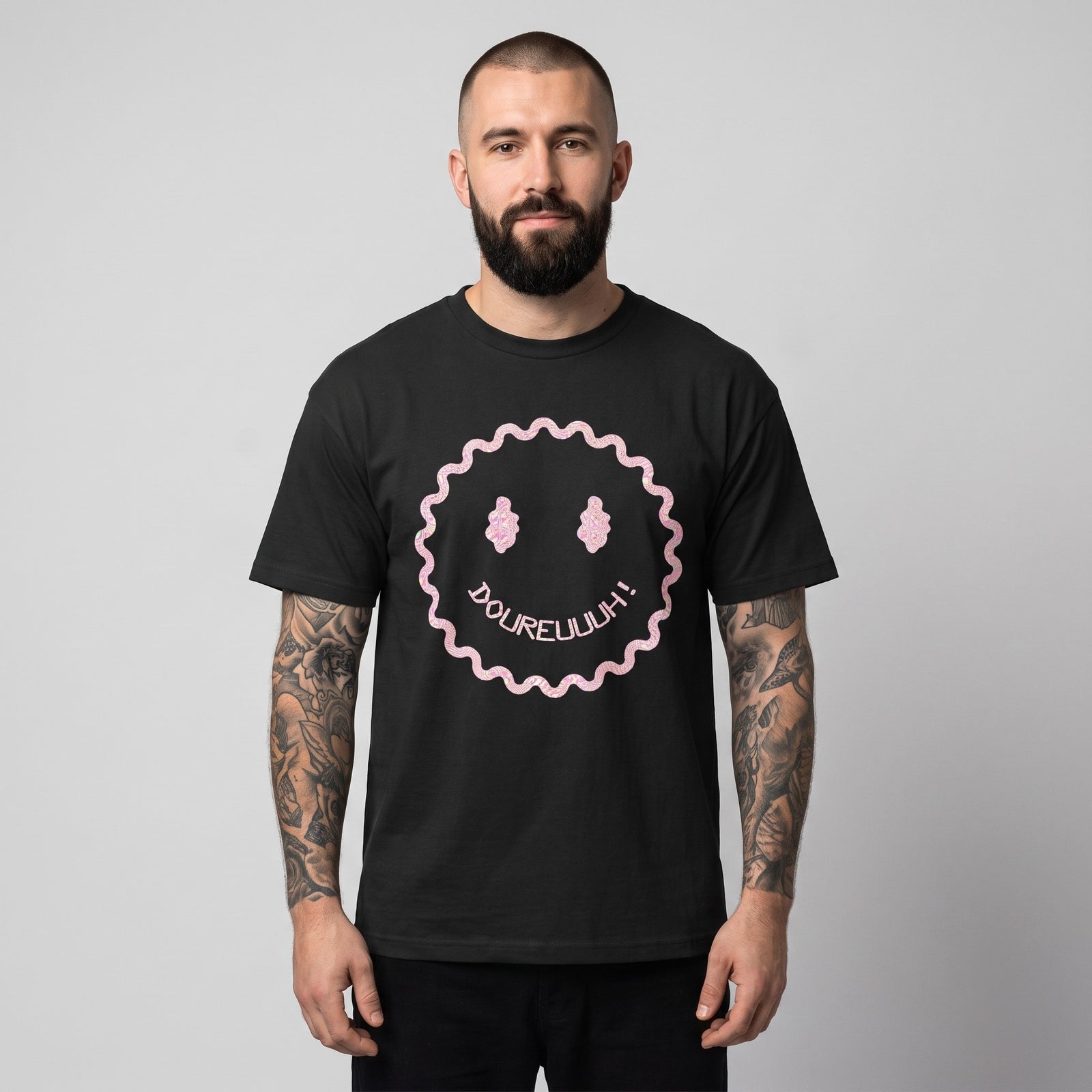 T-shirt Dour Festival DOUREUUUH oversize noir porté par un homme, smiley acid holographique, studio