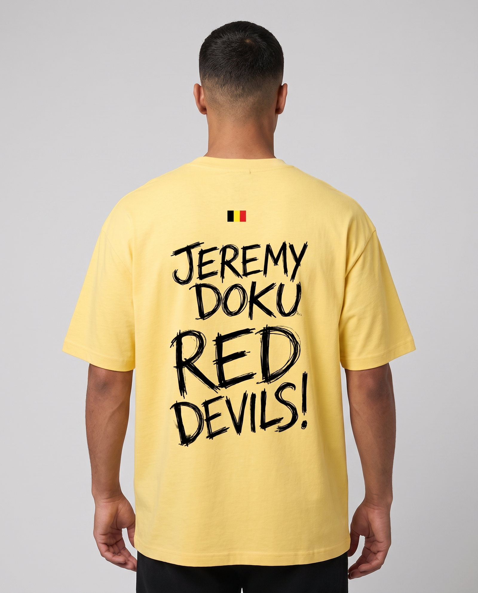 T-shirt oversized Jeremy Doku jaune citron porté en studio, vue de dos avec le lettrage Red Devils