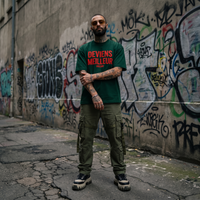 T-shirt Deviens Meilleur vert forêt porté devant un mur de graffitis, look streetwear urbain