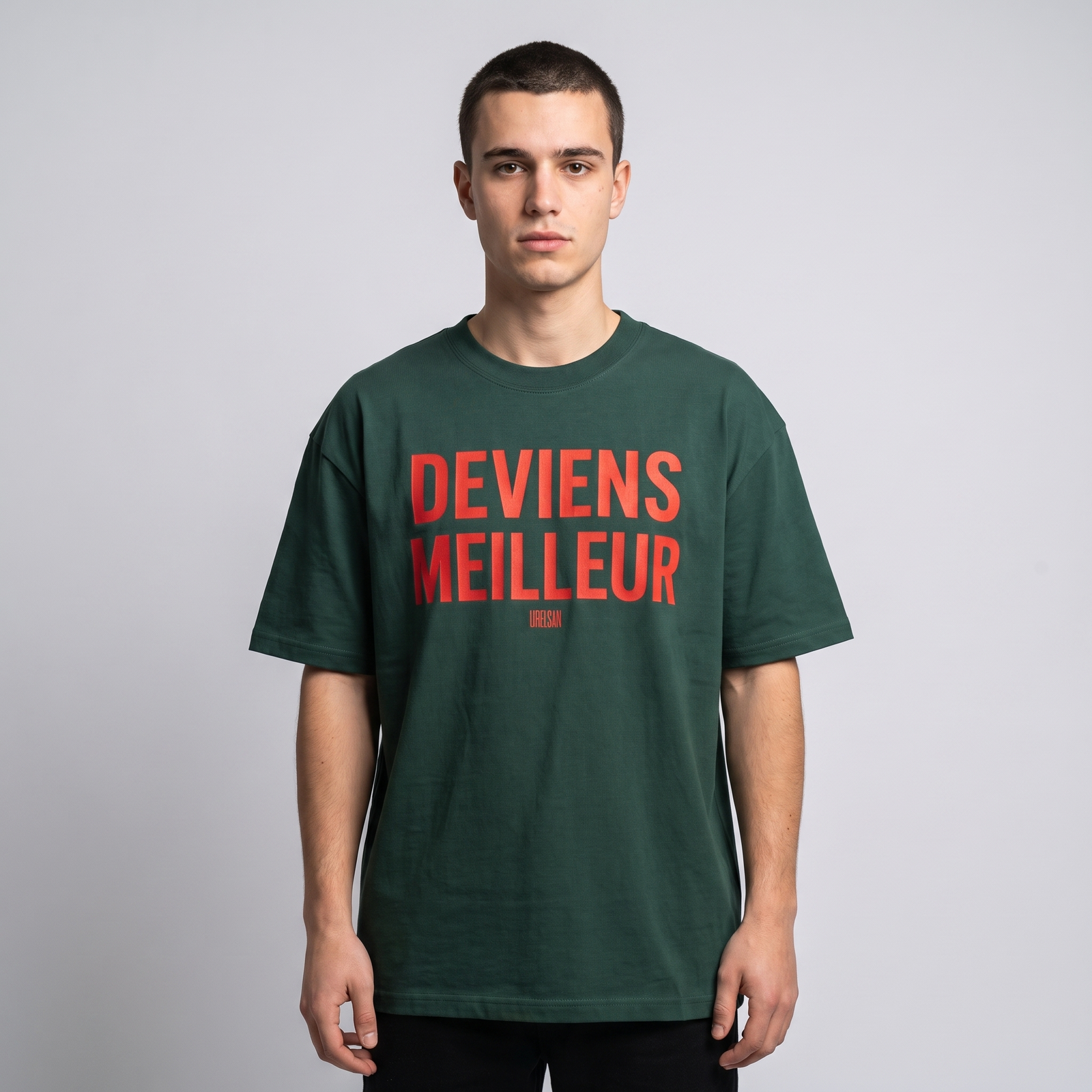 T-shirt oversized vert forêt Deviens Meilleur porté en studio, lettrage rouge sur la poitrine