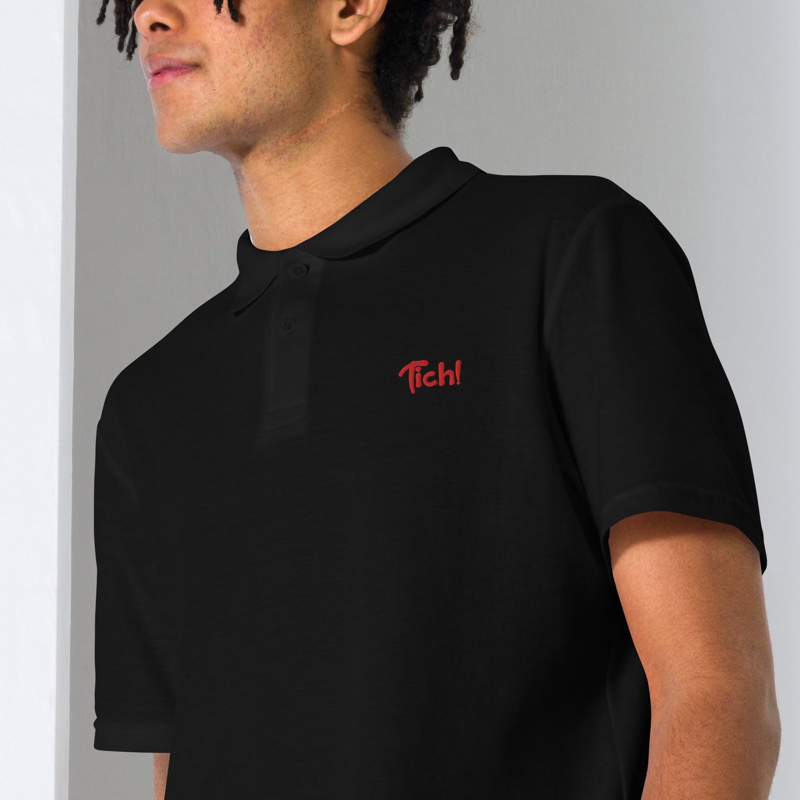 Gros plan de la broderie Tich! sur le polo unisexe noir