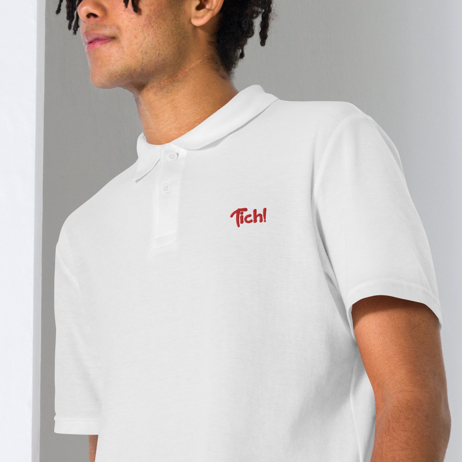 Gros plan de la broderie rouge Tich! sur le polo blanc